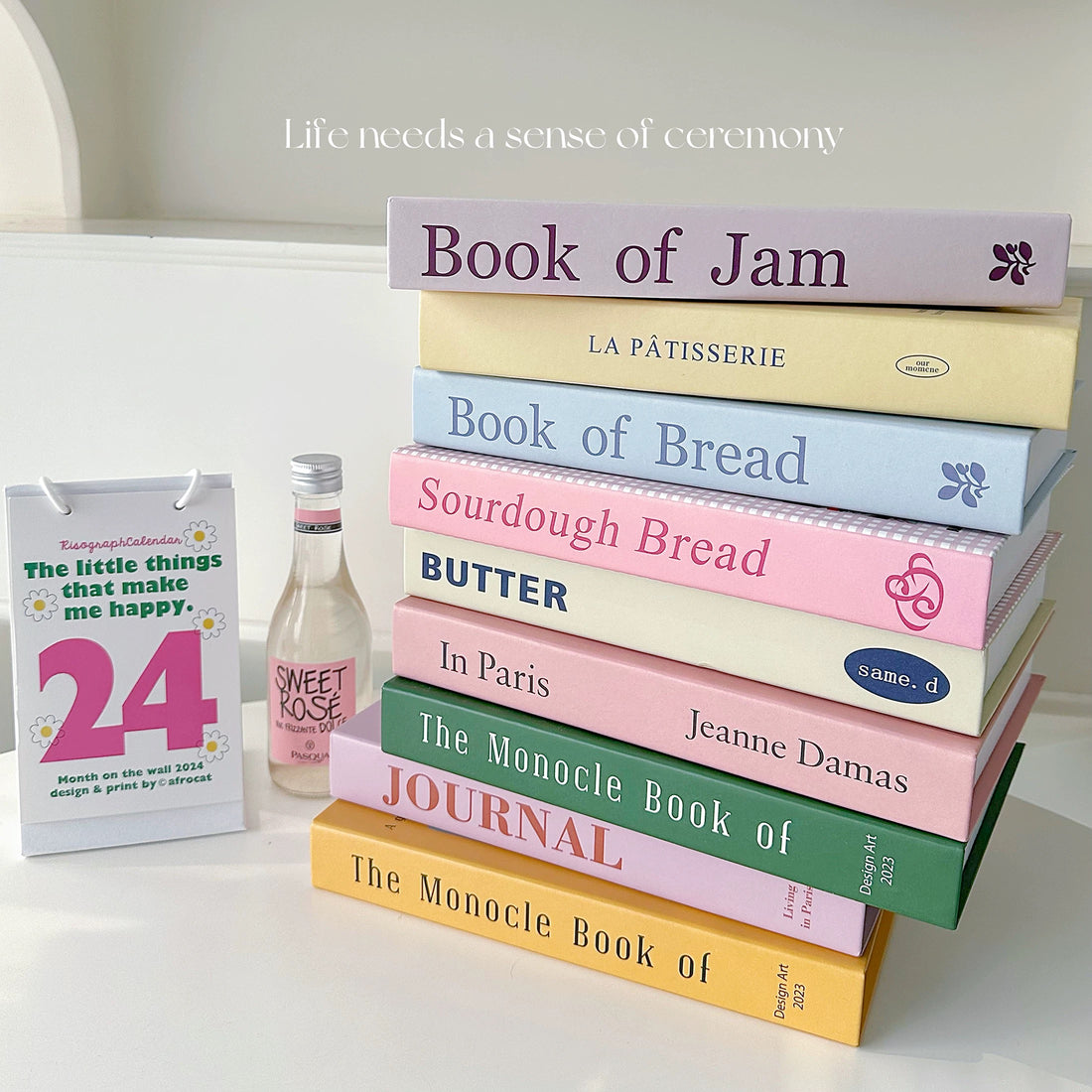 Collection of books on a surface with a bottle of Sweet Rose wine.