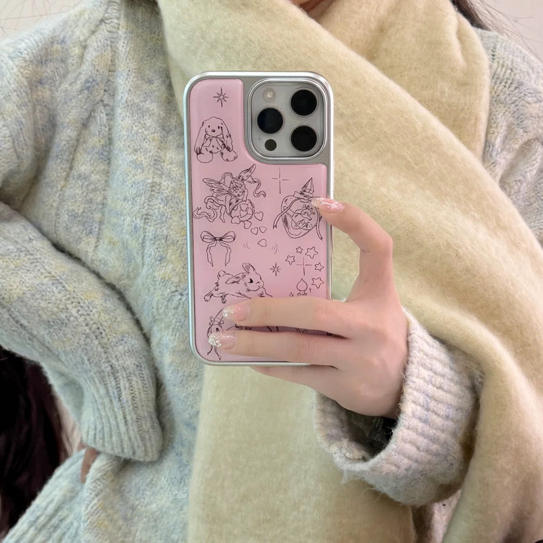 Phone case with cute illustrations held by a person against a tiled wall.