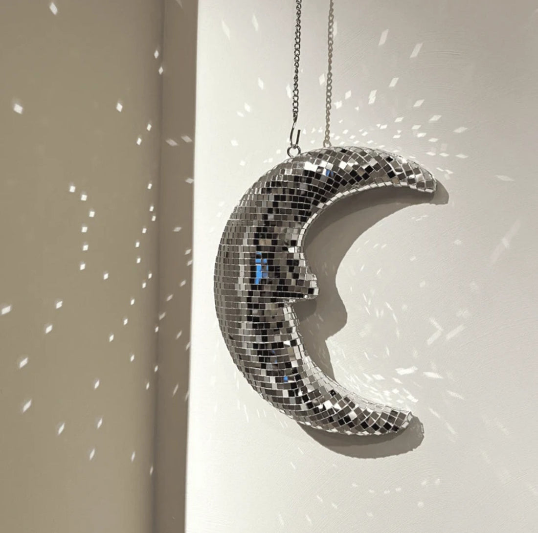 Disco moon pendant reflecting sparkles on white wall