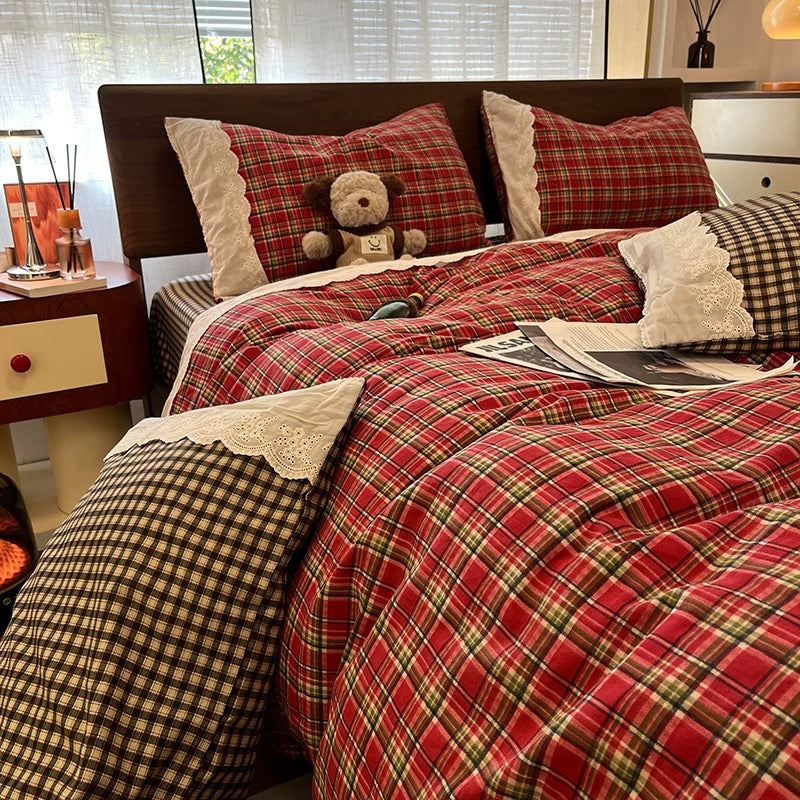 Bed with red plaid comforter and pillows, teddy bear, and bottle on a checkered floor.