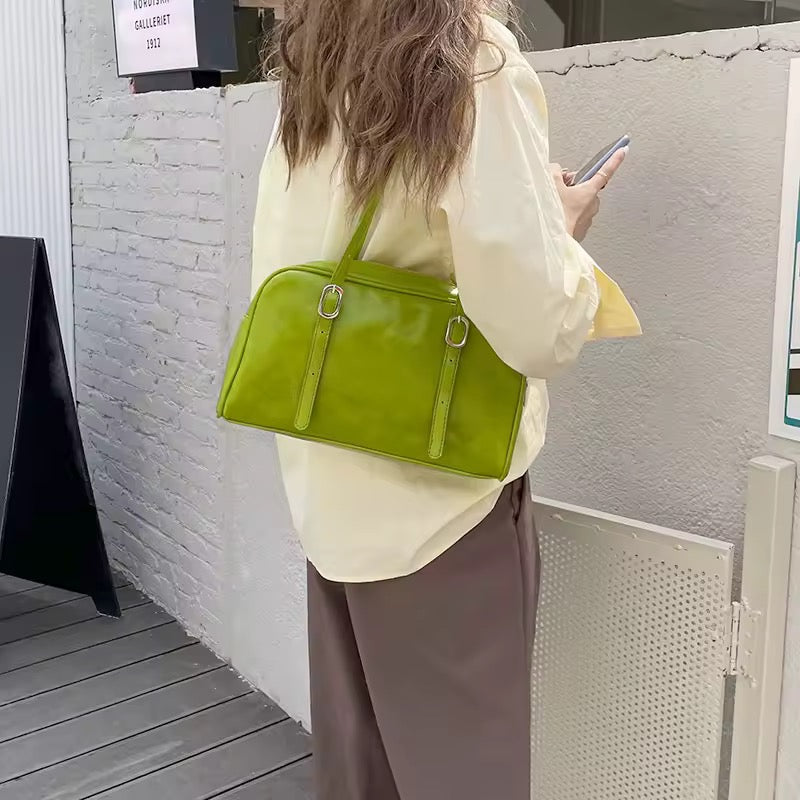 Person holding a green handbag in an outdoor setting