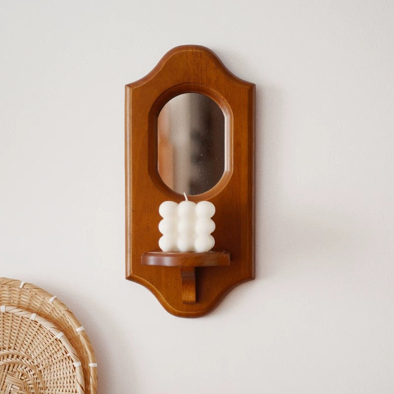 Wooden wall-mounted candle holder with a white candle on a light gray background