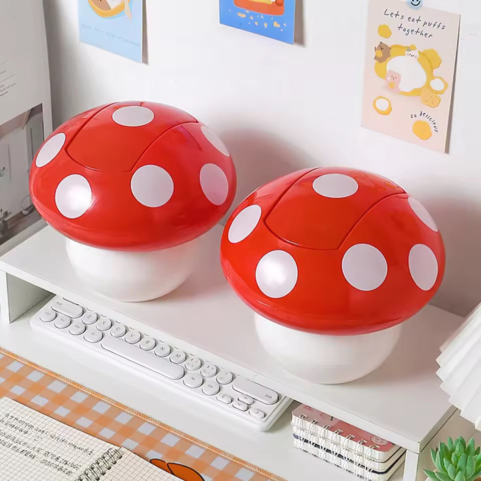 Two red and white mushroom-shaped containers on a shelf with a keyboard and books in the background.