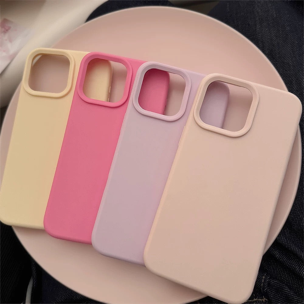 Four phone cases in pink, red, yellow, and gray on a black surface.