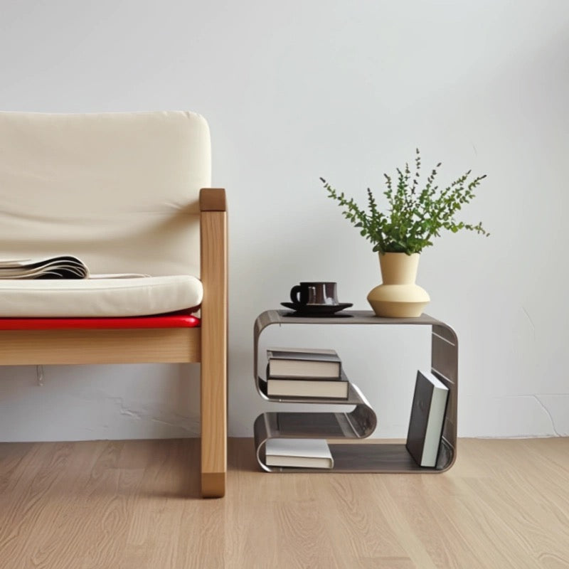Modern chair with a small table holding books and a plant in a minimalistic room.