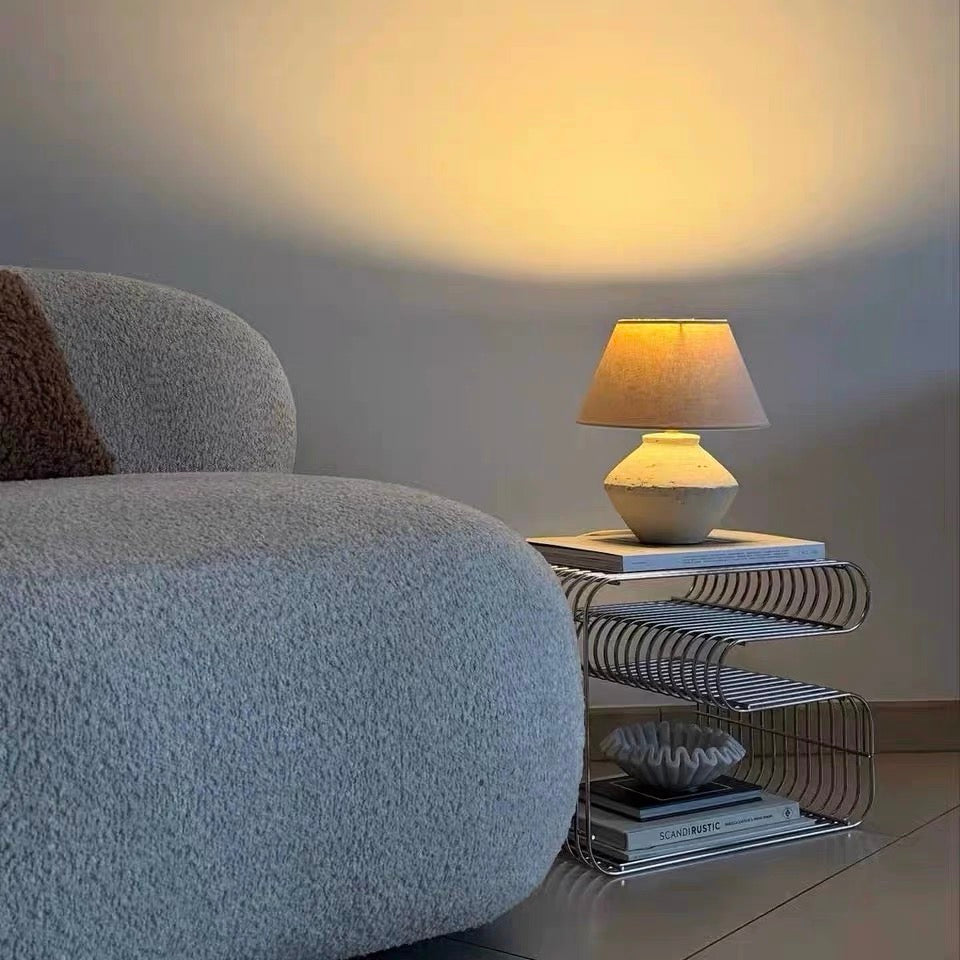 Gray armchair next to a side table with a lamp and books in a room.