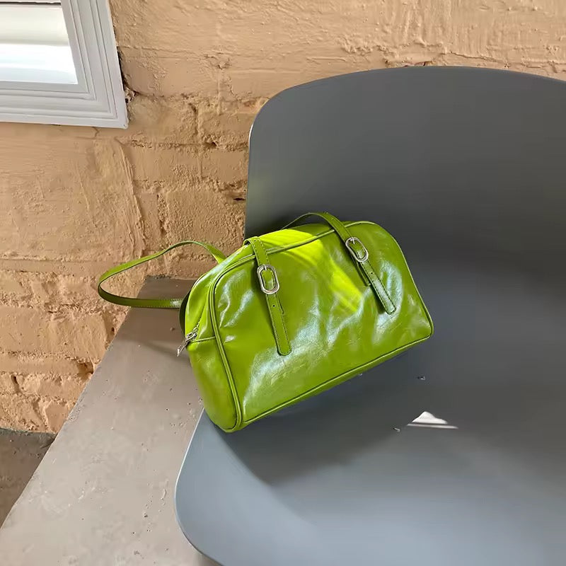Green handbag on a gray chair against a beige wall.