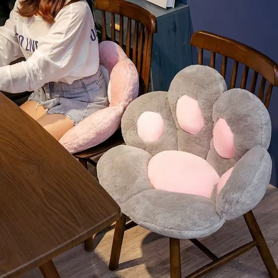 Two paw-shaped chair cushions on wooden chairs in a room setting.