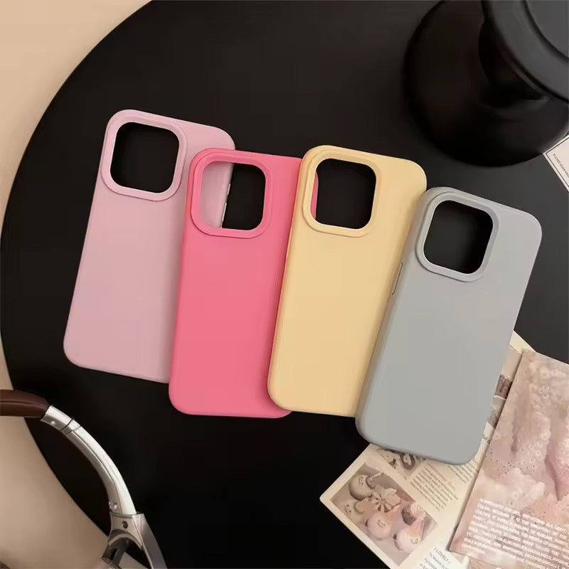 Four phone cases in pink, red, yellow, and gray on a black surface.
