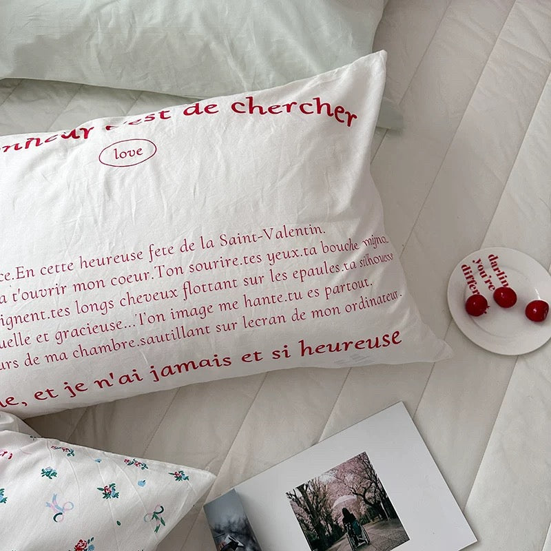 Bedroom with pink and white pillows, a clock, and decorative items on the wall.