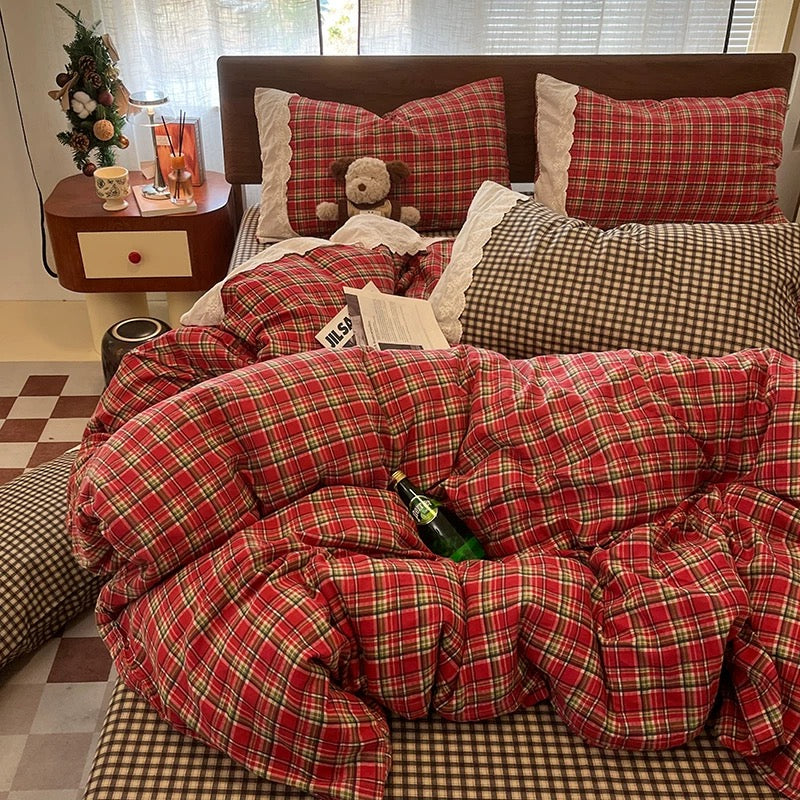 Bed with red plaid comforter and pillows, teddy bear, and bottle on a checkered floor.