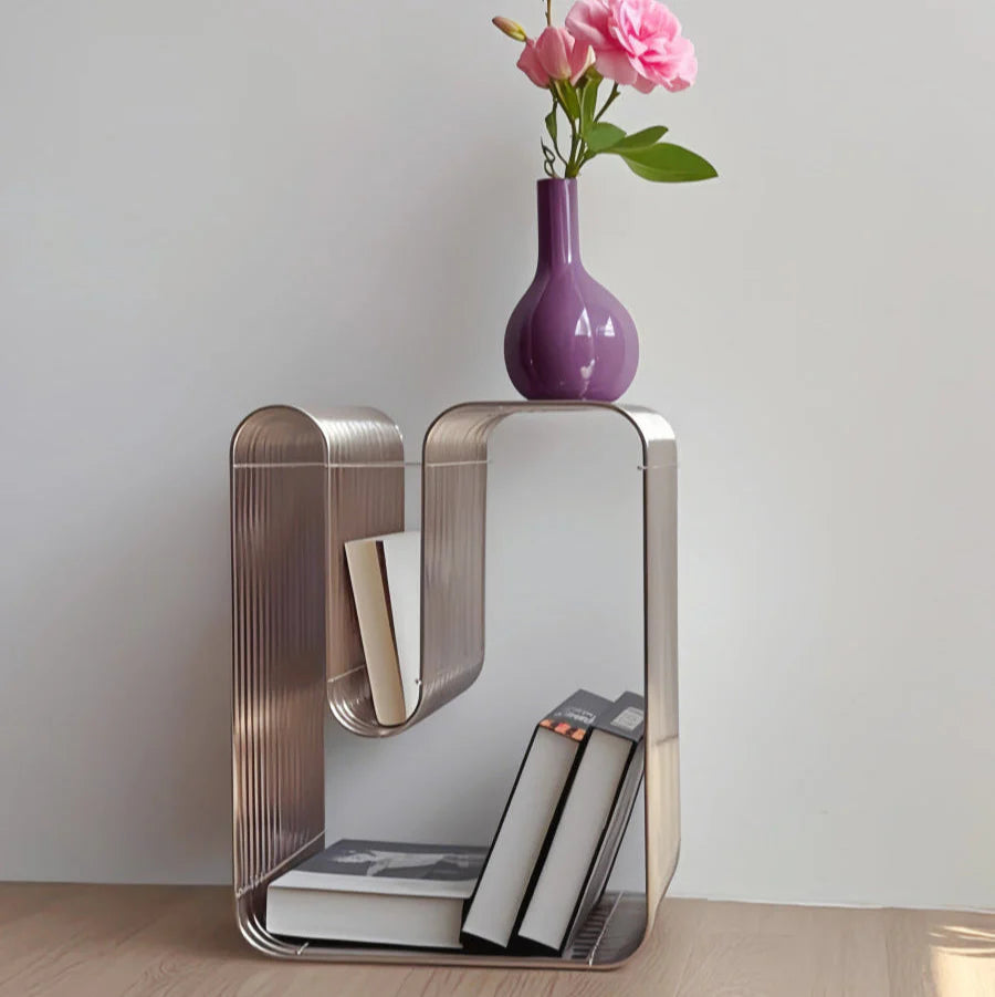 Modern side table with books and a purple vase with flowers on a light gray background