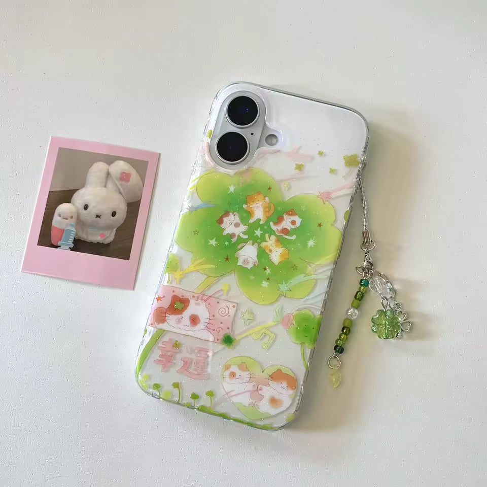 Phone case with cartoon design and charm on a white surface next to a photo of a plush toy.