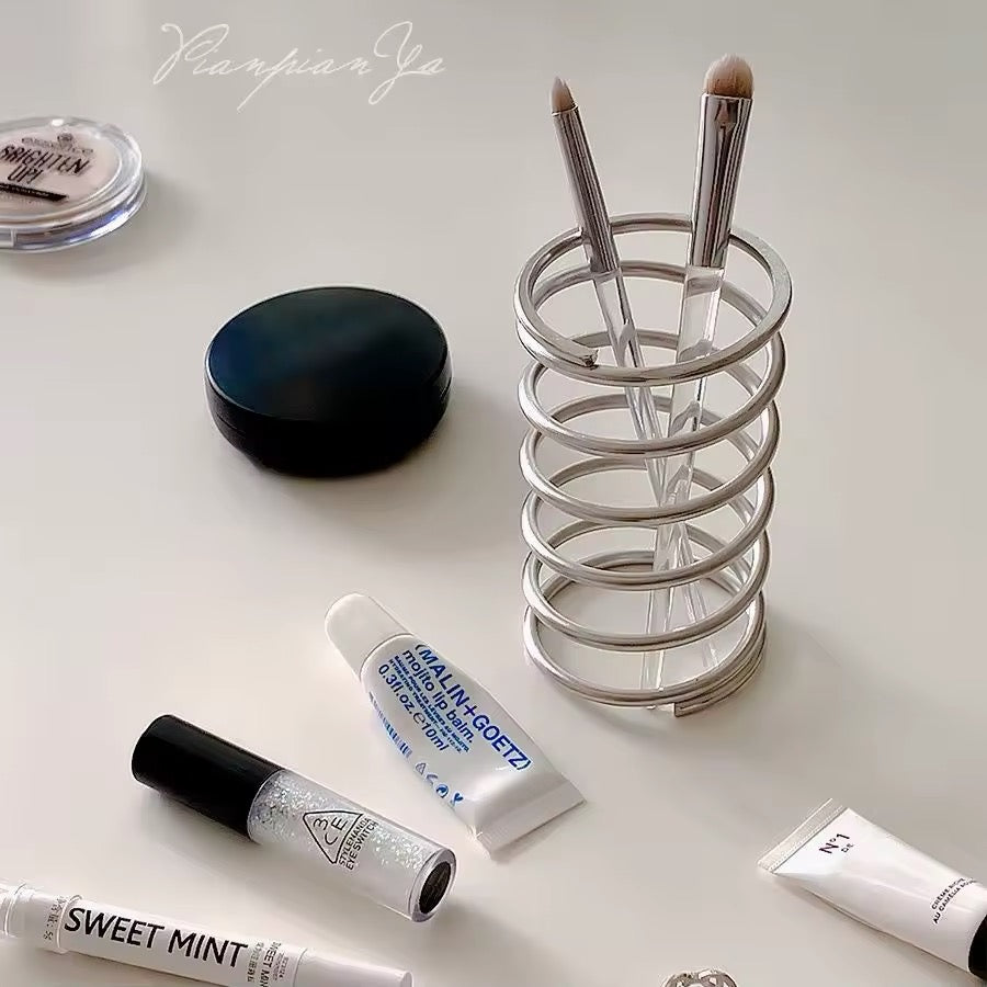 Makeup brushes neatly organized in the stainless steel holder on a vanity table