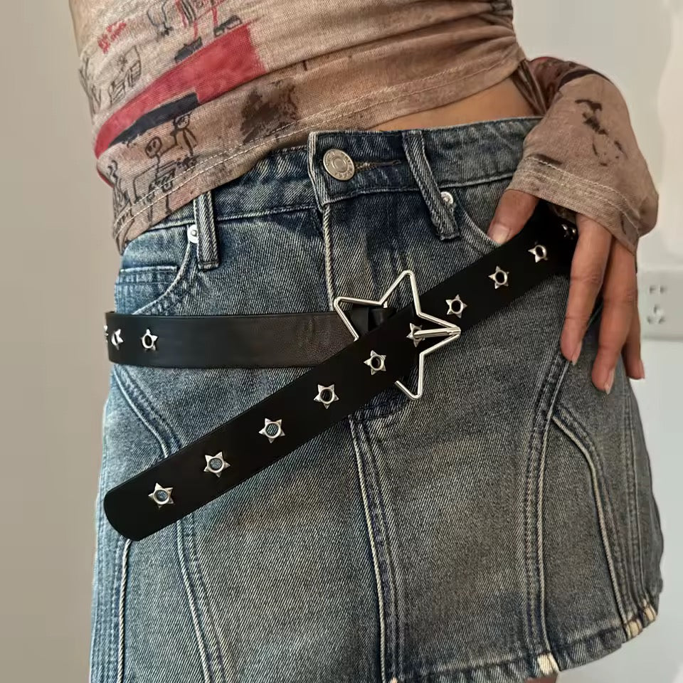 Person wearing a black belt with star designs on blue jeans.