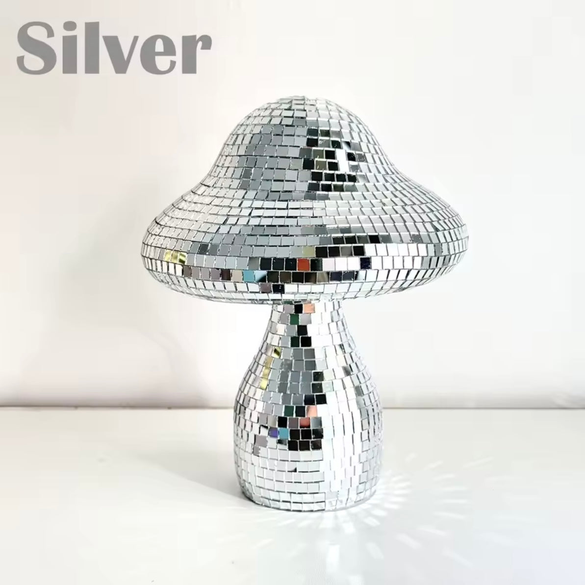 Mushroom-shaped ornament hanging by window, reflecting sunlight.