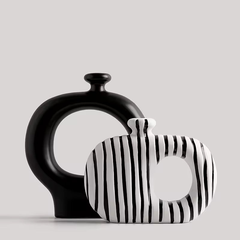 Two ceramic vases, one black and one with black and white striped pattern, on a light gray background.