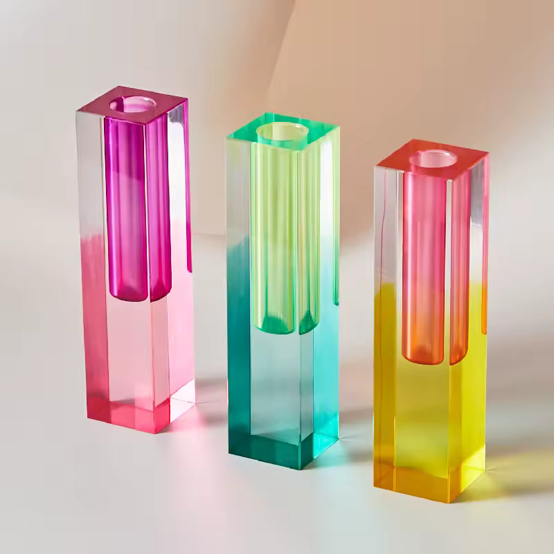 Three colorful glass candle holders on a neutral background