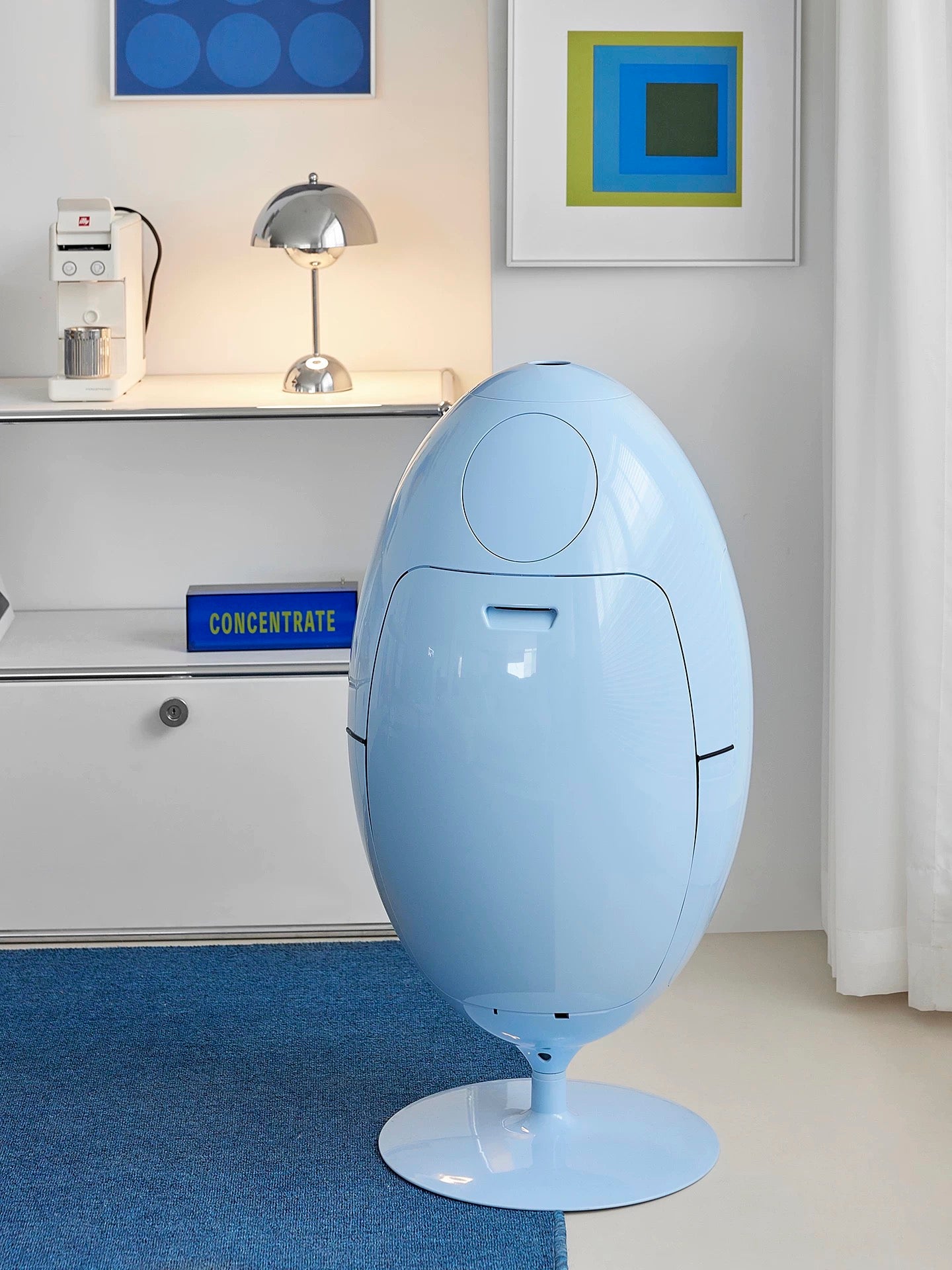 Modern light blue chair in a room with abstract art on the wall.