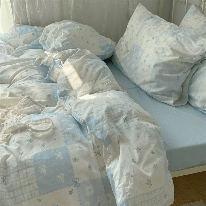 Blue patchwork cotton bedding styled with pastel pillows and aesthetic wall art.
