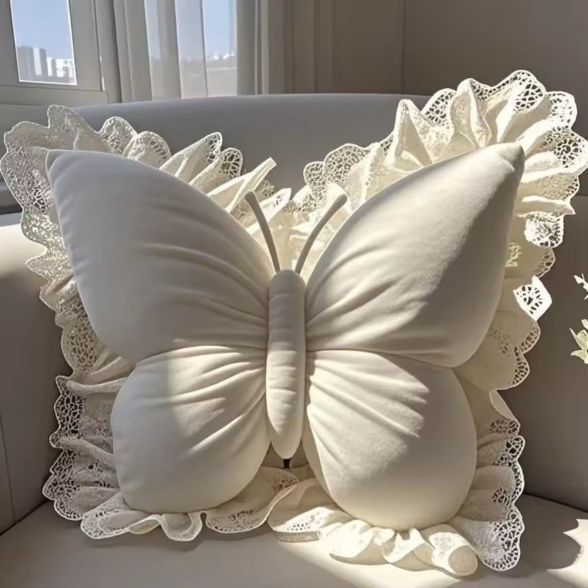 White butterfly-shaped pillow with lace details on a light-colored couch.