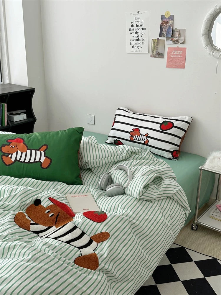 Bed with green and white striped bedding featuring cartoon dog characters, in a room with a desk and window.