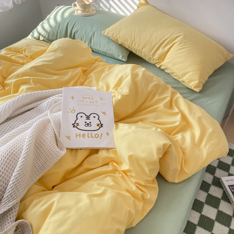 Yellow bedding set with a 'Hello!' card on a bed