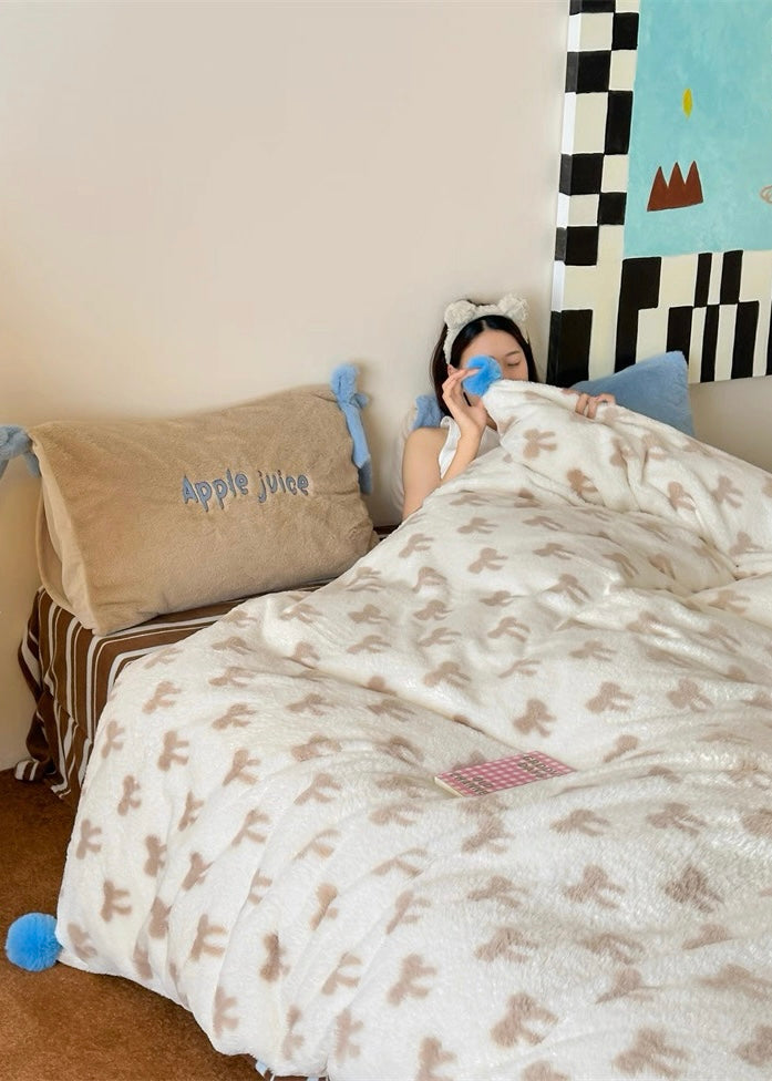Person lying in bed under a blanket with teddy bear pattern, wearing gloves and a headband.
