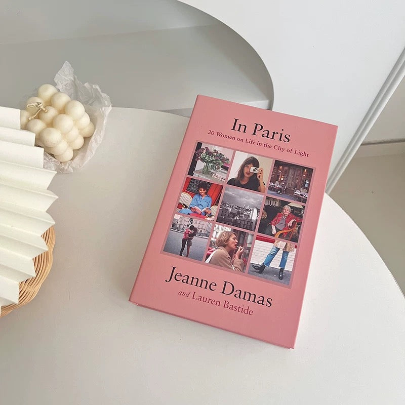 Book titled 'In Paris' by Jeanne Damas and Lauren Bastide on a white surface with decorative elements.