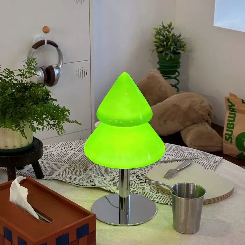 Green tree-shaped lamp on a table with a cup and tissue box in a room setting.