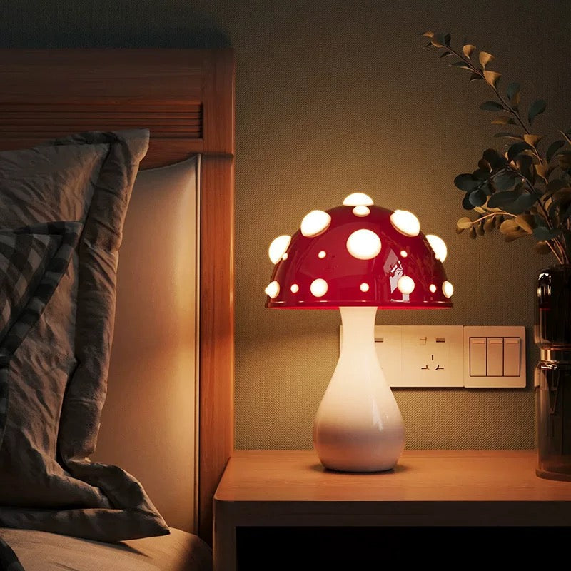 Red mushroom-shaped lamp on a bedside table next to a bed