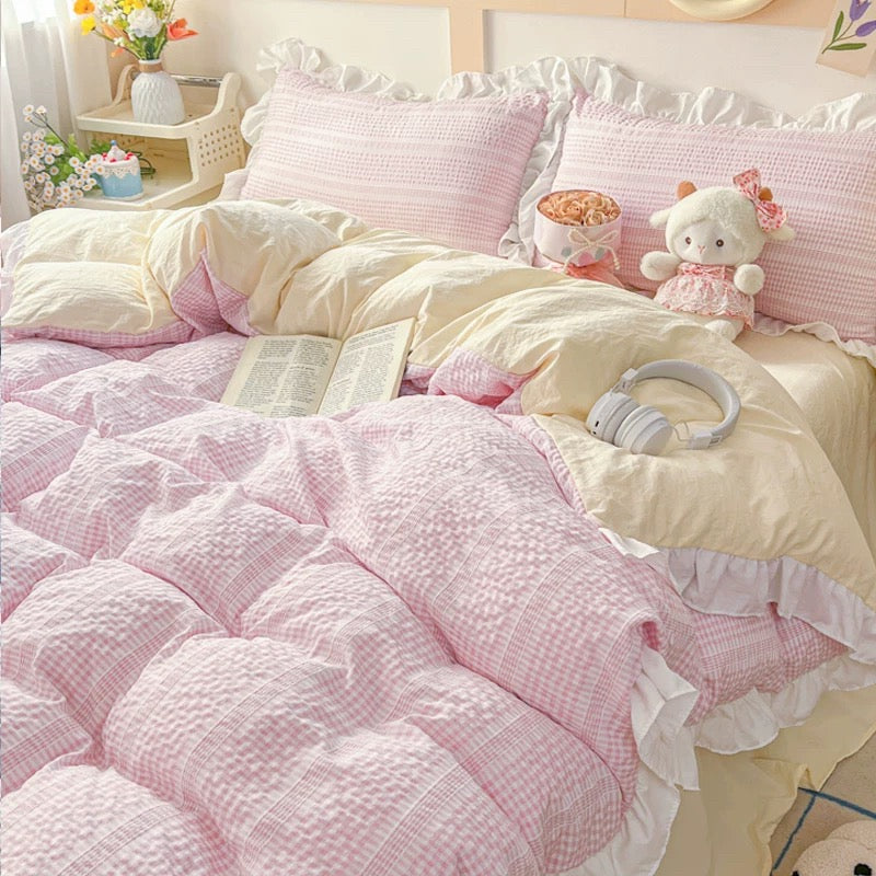 Pink and white bedding set with plush toys on a bed in a bedroom.