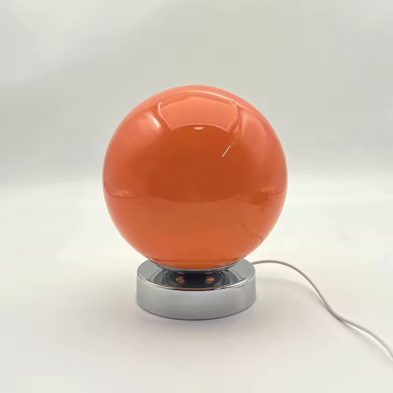 Orange spherical lamp with a metallic base on a white background