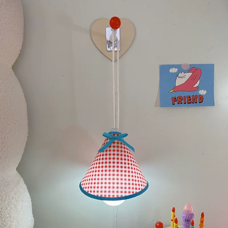 Red and white checkered lampshade with blue trim hanging on a wall.