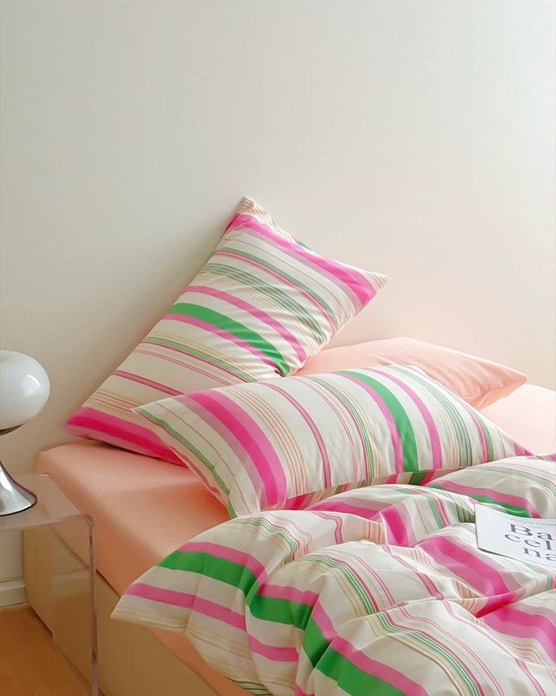 Striped bedding and pillows on a bed in a bedroom setting.