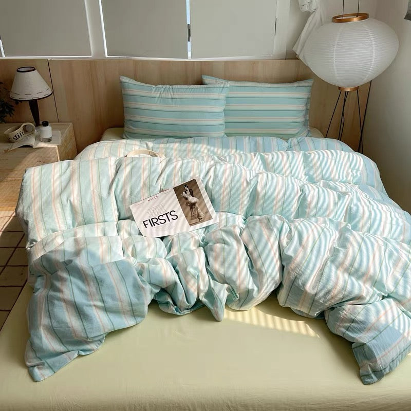 Teal and white striped bedding set on a bed with a 'FIRSTS' card.