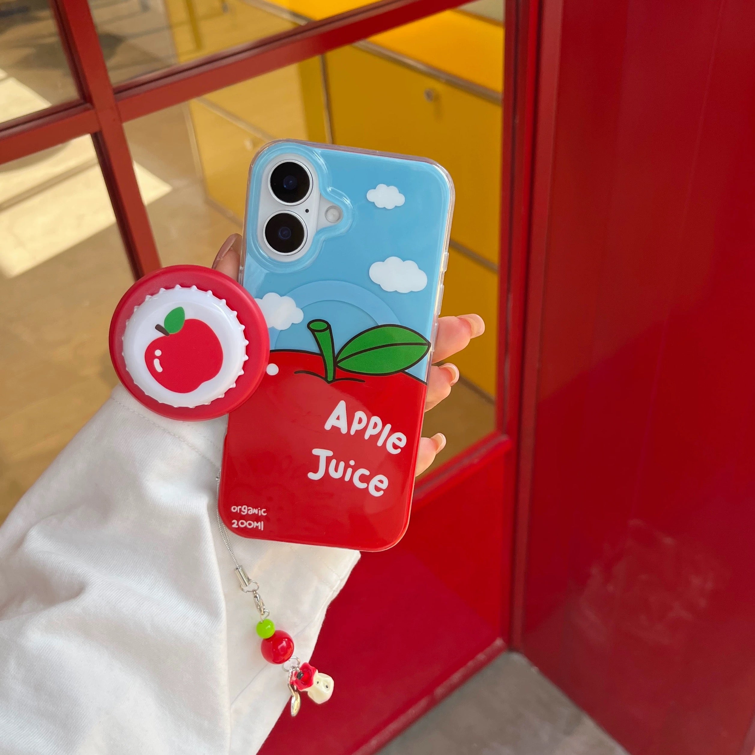 Phone case with apple design and 'Apple Juice' text, held against a red and yellow background.