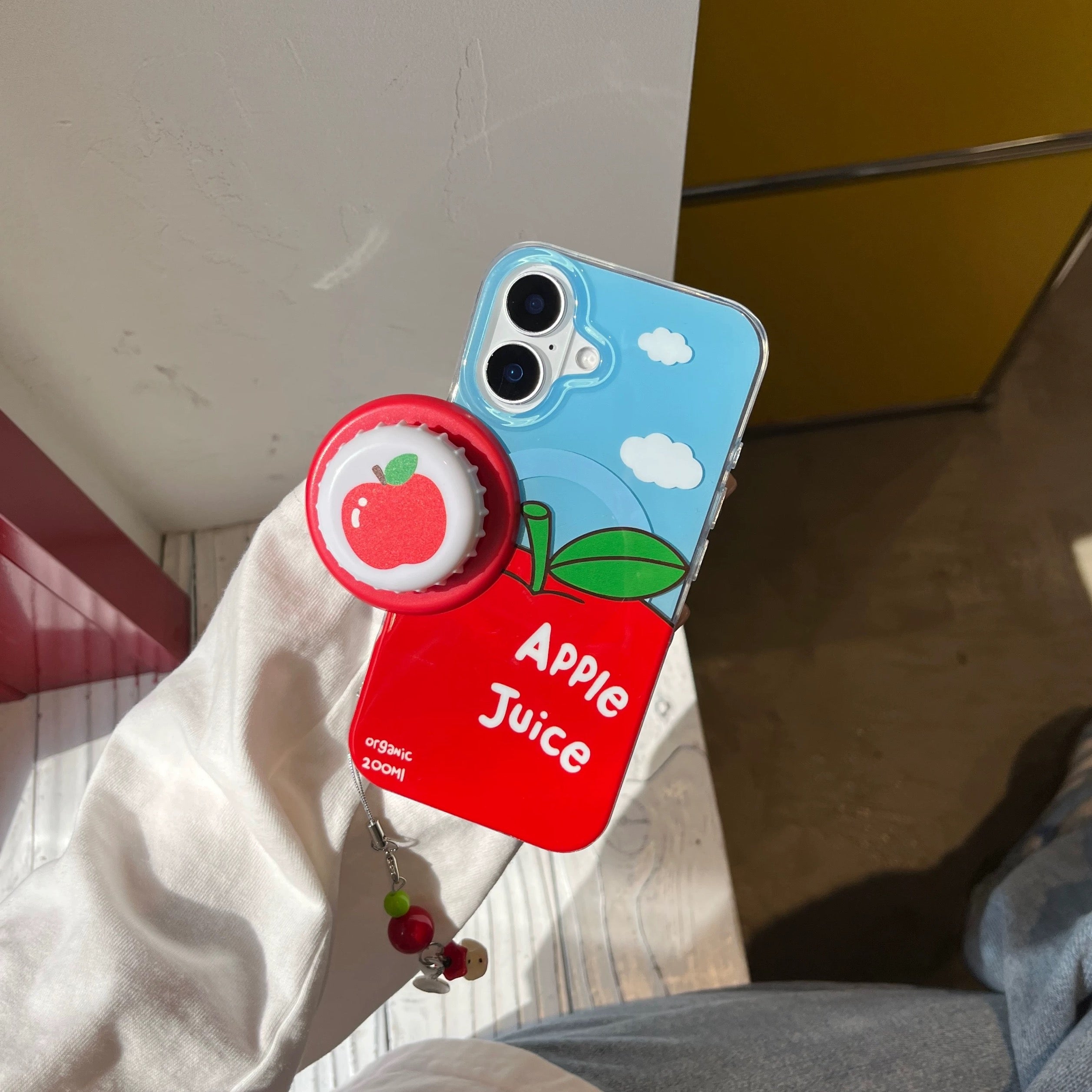 Phone case with apple design and 'Apple Juice' text held by a person.