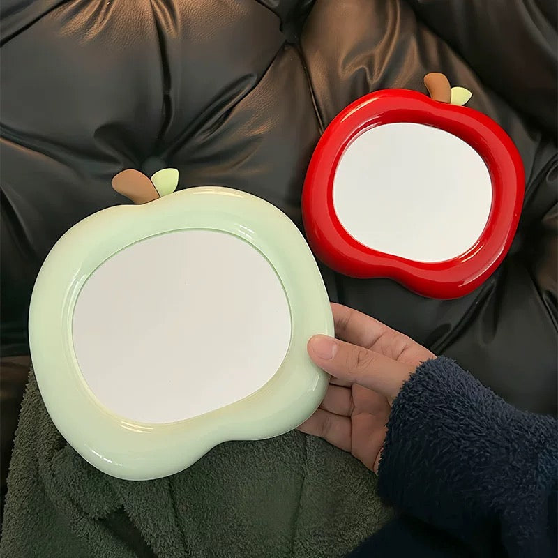 Cute apple-shaped mirror in red color on aesthetic desk with soft lighting
