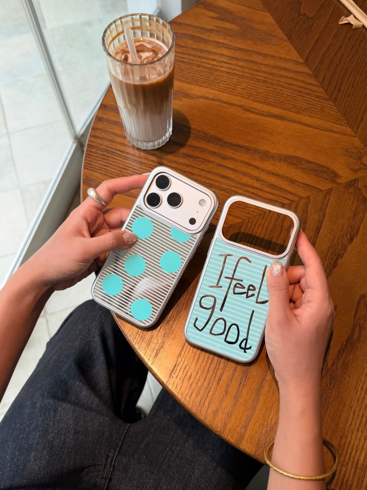 Two aqua iPhone cases are held side by side, with large dots on the left and Feel Good lettering on the right.
