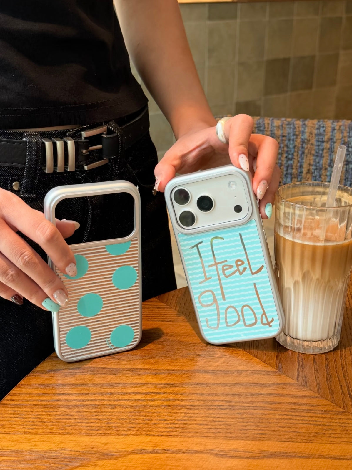 An aqua polka dot iPhone case stands beside the Feel Good design, with light reflecting across both backs.