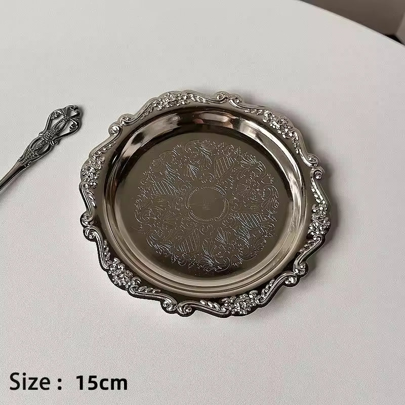 Decorative silver tray with intricate designs on a white surface
