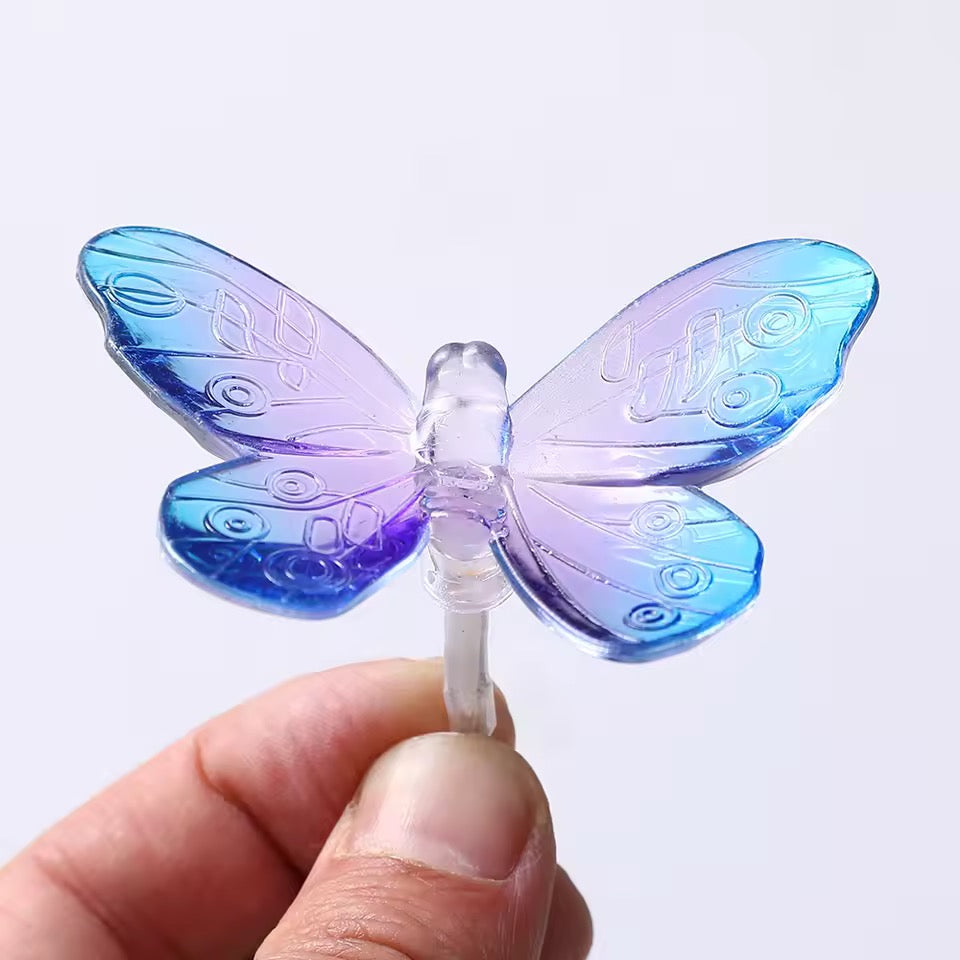 Blue and purple butterfly-shaped object held by a hand against a white background