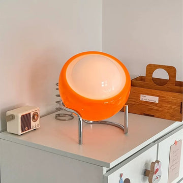Orange lamp on a shelf with a retro radio and wooden box in the background