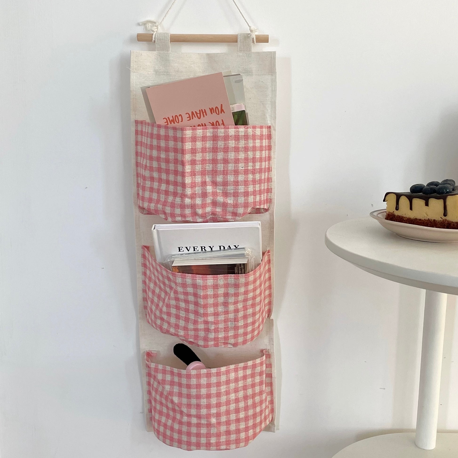 Red and white checkered hanging organizer with pockets on a white wall.