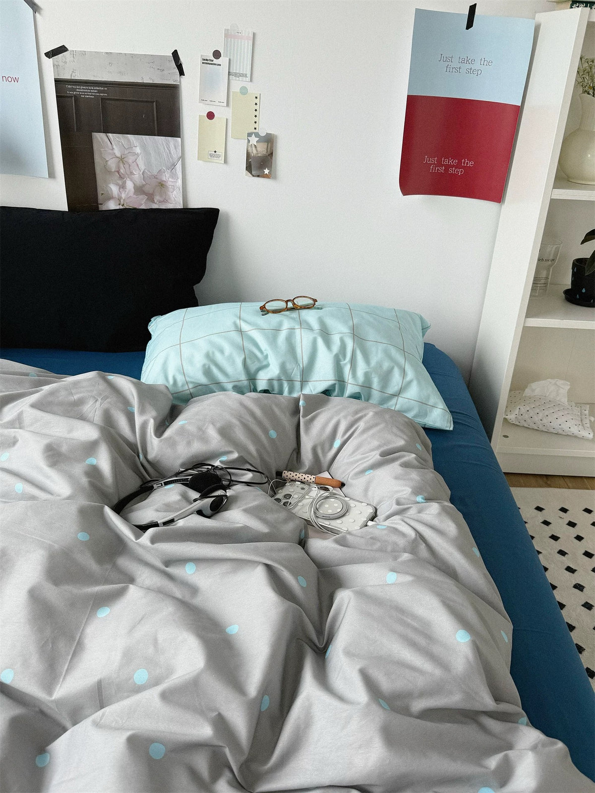 Black and blue check pillowcases above the gray dotted cover and blue flat sheet.