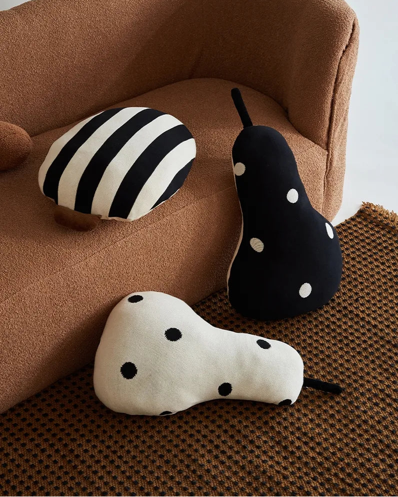 Two decorative pillows, one with black and white stripes and the other with black polka dots, on a white cushion.