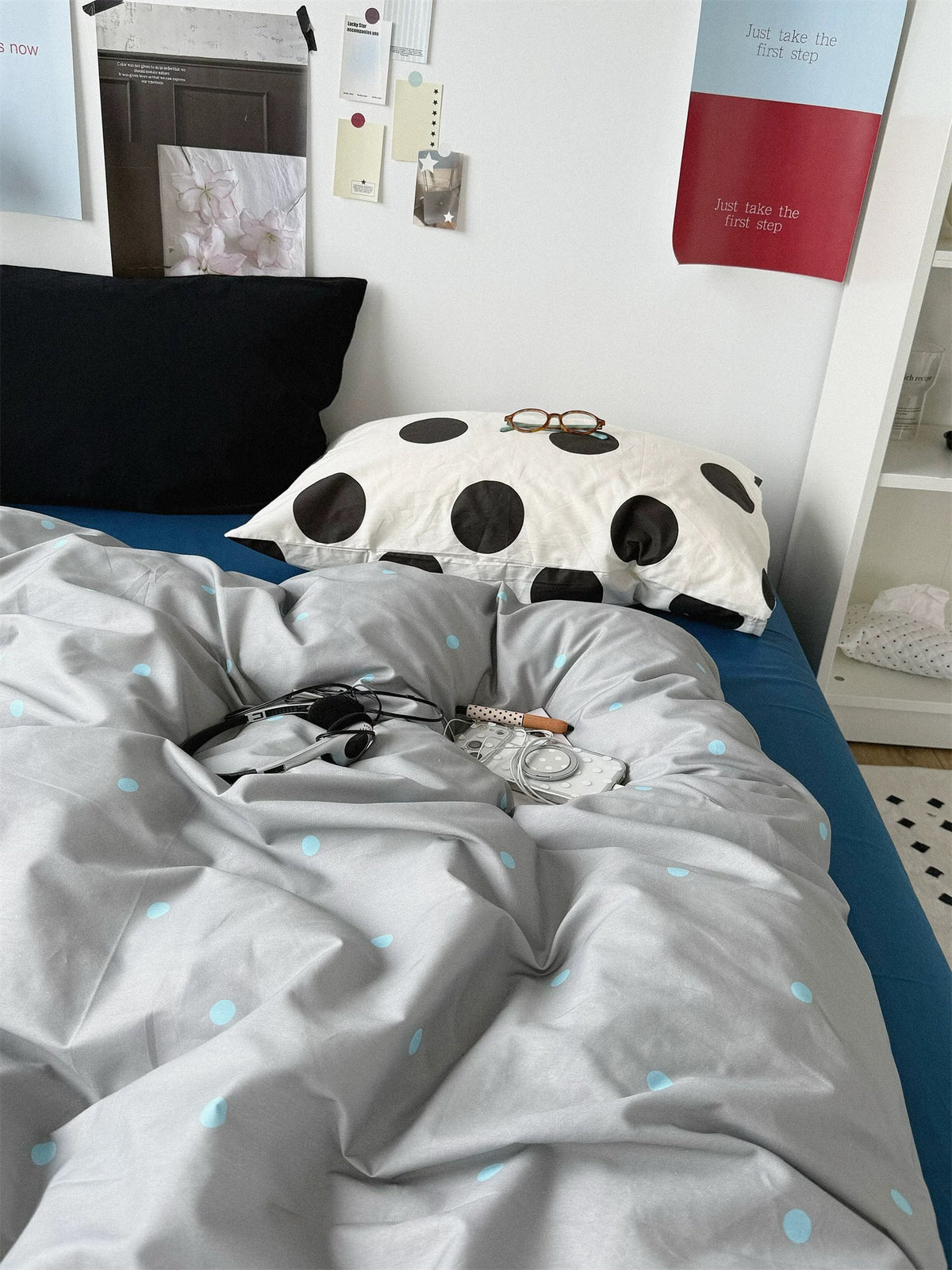 Black and large black dot pillowcases behind the gray blue dotted bedding.