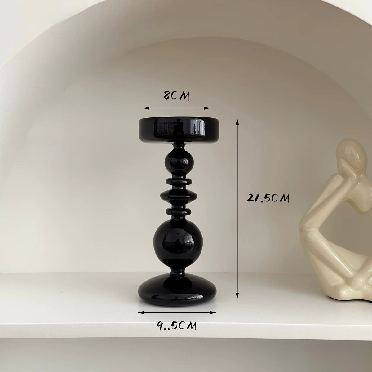 Black decorative pedestal with measurements on a white shelf