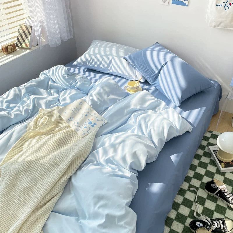 Blue bedding set with duvet cover and pillowcases styled in a cozy minimalist bedroom.